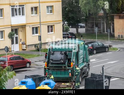 Sibiu City, Rumänien - 29. Mai 2024. Arbeiter, die Müllcontainer mit Müll ausziehen, Straßenreinigung, Männer, die Abfall aus Mülltonnen laden Stockfoto