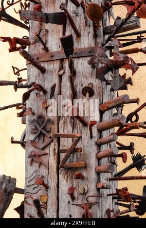 Nägel und verschiedene eiserne Gegenstände, die im alten Holzbalken stecken Stockfoto