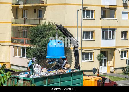 Sibiu City, Rumänien - 27. Mai 2024. Arbeiter keimen Container mit selektivem Müll in den Anhänger, Straßenreinigung, Männer laden Abfall aus Mülltonnen Stockfoto