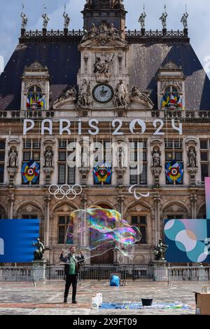 Paris, Frankreich 05.22.2024 Unbekannter Blasenkünstler, der vor dem Pariser Rathaus auftritt. Das Rathaus mit den Olympischen Ringen und Paris Stockfoto