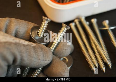 Der Arbeitsprozess des Bauherstellers. Schrauben mit einer Stahlscheibe in der Hand der bilder. Stockfoto