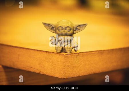 Madrid, Spanien 7. Mai 2024 DIN Grogu, Star Wars Spielzeugheld aus recyceltem Kunststoff isoliert auf gelbem Hintergrund. Happy Baby Yoda aus der Disney-Serie. Stockfoto