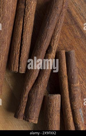 Flache Nahaufnahme von Lebensmittelaufnahmen von Zimtstäbchen auf einem Akazienschneidebrett, aromatische Gewürze auf hölzernem Hintergrund Stockfoto