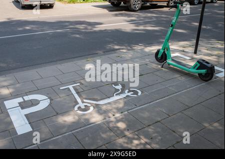 Reihen grüner Elektroroller, die auf einem Bürgersteig der Stadt geparkt sind. Mietfahrzeuge für den Personenverkehr. Litauen Vilnius Stockfoto