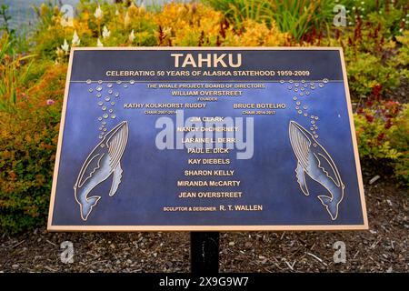 Namensschild von Tahku, einer Bronzeskulptur eines brechenden Buckelwals, die 50 Jahre Alaska-Staatlichkeit feiert, im Overstreet Park an der Uferpromenade Stockfoto