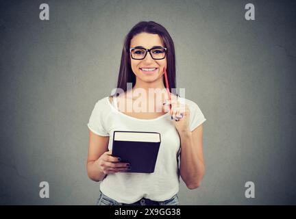 Kreative, intelligente, begeisterte Frau mit Notebook und Stift Stockfoto