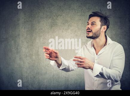 Ein junger Geschäftsmann, der versucht, etwas zu fangen Stockfoto