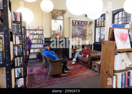 Kunden lesen am offenen Feuer bei Barter Books, einem berühmten und riesigen Second-Hand-Buchladen im ehemaligen Bahnhofsgebäude in Alnwick Northumberland Stockfoto