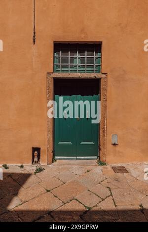 Eine klassische Straßenszene in einer italienischen Stadt in der Toskana, Italien an einem sonnigen Tag, mit einer traditionellen Tür in ein gemaltes Gebäude und schönen Farben. Stockfoto