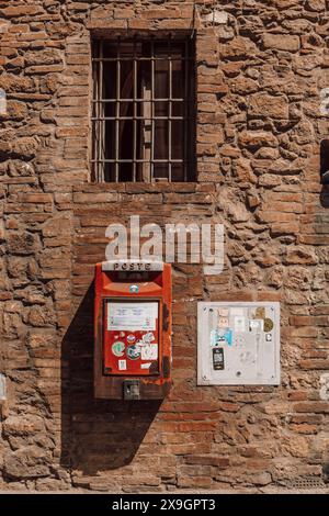 Briefkasten an einer Wand vor einem Haus auf der Straße eines malerischen italienischen Dorfes in der ländlichen Toskana in Italien an einem sonnigen Tag mit Backsteinmauern und Schatten. Stockfoto