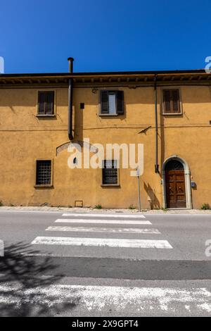 Eine klassische Straßenszene in einer italienischen Stadt in der Toskana, Italien an einem sonnigen Tag, mit einer traditionellen Tür in ein gemaltes Gebäude und schönen Farben. Stockfoto