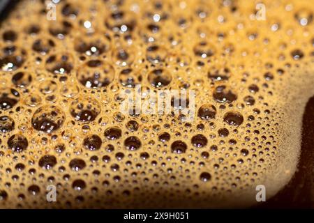 Strukturierte Schaumblasen mit Bokeh-Effekt auf der Oberfläche einer heißen Kaffeetasse Stockfoto