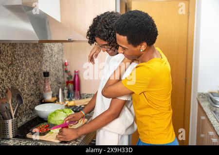 Mann, der sich von seinem schwulen Paar umschließt, während er gesunden Salat zu Hause kocht Stockfoto