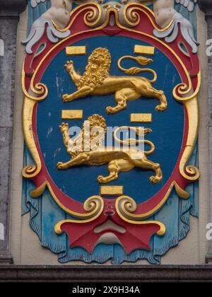 Nahaufnahme eines Wappens mit goldenen Löwen und bunten Verzierungen, historischen Häusern in Hoorn und Schiffen im Hafen von hoorn, niederlande Stockfoto