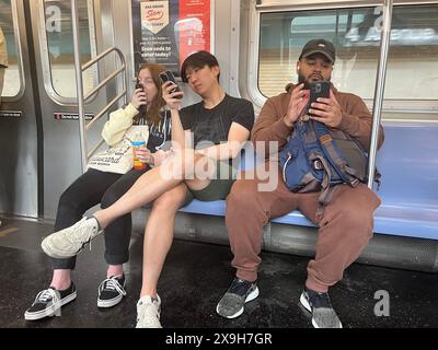 U-Bahn-Fahrer verstrickten ihre Handys, während sie einen F Train in Brooklyn, New York, fuhren. Stockfoto