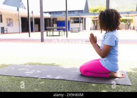 Biracial Girl praktiziert Yoga in der Schule, mit Kopierraum Stockfoto