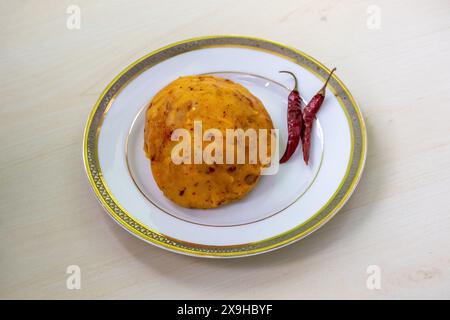Köstliches Aloo Bhorta auf einem weißen Teller auf hölzernem Hintergrund. Alu Vorta ist ein traditionelles Essen aus Bangladesch und der Region Bengalen in Indien. Stockfoto