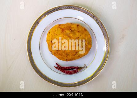 Köstliches Alu Bharta auf einem weißen Teller auf hölzernem Hintergrund. Aloo Bhorta ist das einfachste und traditionellste Essen aus Bangladesch Stockfoto