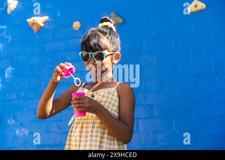 Biracial Girl, das eine Sonnenbrille und ein Sommerkleid trägt, genießt Outdoor-Spielzeit mit Kopierraum Stockfoto