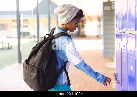 Ein birassischer Junge in der Schule öffnet seinen Spind Stockfoto