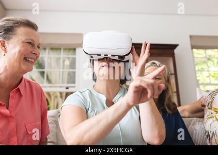 Verschiedene ältere Freundinnen erforschen die virtuelle Realität zu Hause Stockfoto