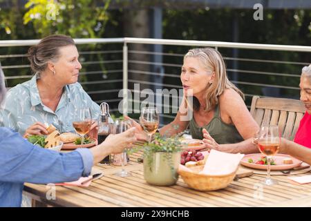 Verschiedene ältere Freundinnen genießen Essen im Freien, plaudern und lachen Stockfoto