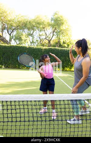 Im Freien haben Mutter und Tochter auf dem Tennisplatz eine Rassentreue Stockfoto