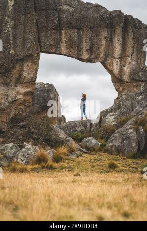 Eine Frau steht vor einer großen Felsformation und blickt auf die Landschaft, den Huayllay Stone Forest, Peru. Stockfoto