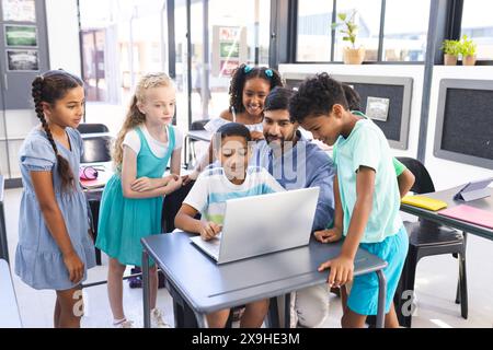 Ein junger asiatischer Lehrer führt die Kinder durch den Laptop Stockfoto