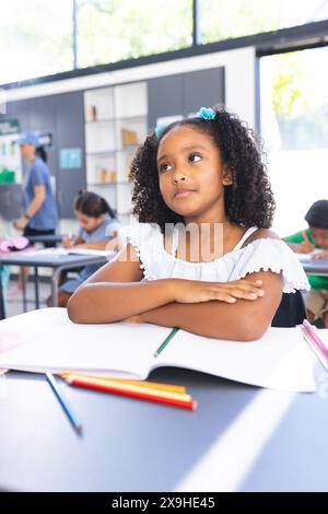 Ein birassisches Mädchen mit lockigen Haaren sitzt tief in Gedanken am Schreibtisch Stockfoto