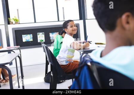 Birassischer Junge lächelt, schaut zurück auf Klassenkameraden im Klassenzimmer Stockfoto