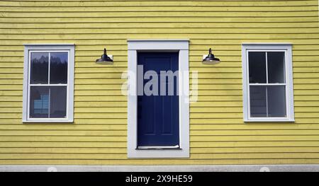 Fassade eines gelben Schrankhauses mit Tür und zwei Fenstern Stockfoto