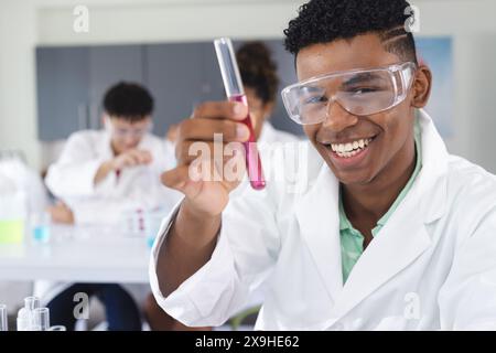 Ein birassischer Teenager untersucht ein Reagenzglas in einem High School Labor Stockfoto