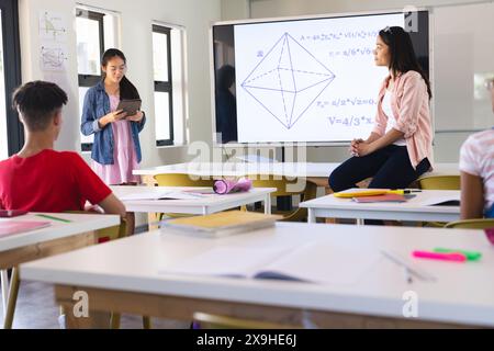 Eine junge birassische Lehrerin unterrichtet Geometrie in einem hellen Klassenzimmer Stockfoto