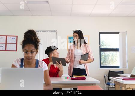 Teenager-birassischer Junge und Teenager-undefiniertes Mädchen in einer High School-Umgebung. Die Schüler engagieren sich für kollaboratives Lernen und verbessern so ihre Bildungsexperten Stockfoto