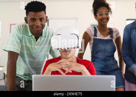 Teenager-Biracial-Jungen und Teenager-Mädchen in einem Klassenzimmer in der High School. Sie erkunden Virtual-Reality-Technologie während eines interaktiven Schulunterrichts. Stockfoto