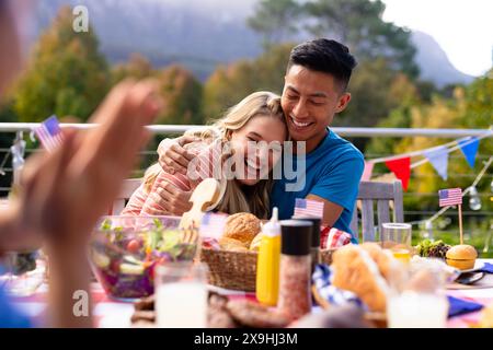 Glückliche, vielfältige Gruppe von Freunden, die mit den Fahnen der usa zu Abend essen Stockfoto