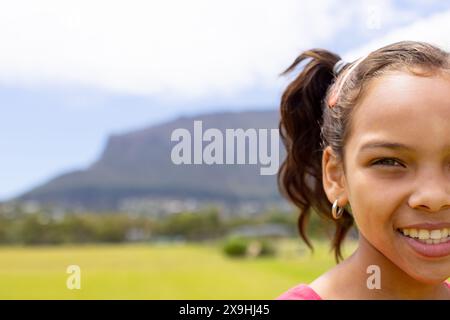 Birassisches Mädchen mit einem hellen Lächeln, draußen mit Bergkulisse, mit Kopierraum Stockfoto