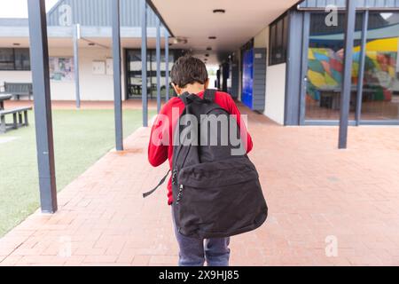 In der Schule ging ein junger männlicher Student mit rotem Hoodie und Jeans draußen Stockfoto