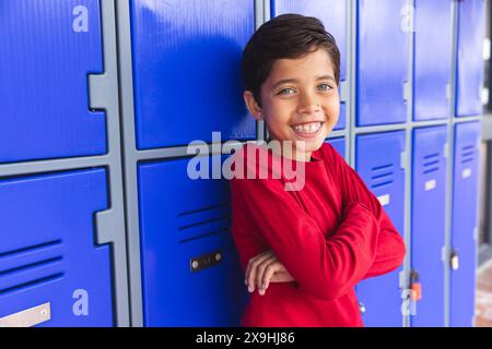 In der Schule, draußen, steht ein junger männlicher Schüler mit birassischem Hintergrund und lächelt Stockfoto