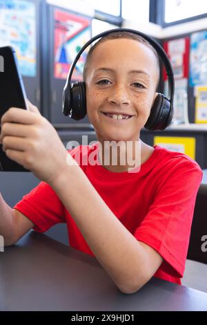 Biracial Boy genießt Musik über Kopfhörer in der Schule mit einem Tablet Stockfoto