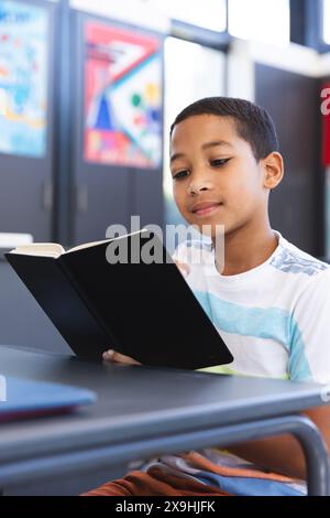 Biracial Boy liest ein Buch in der Schule Stockfoto