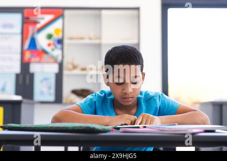 Biracial Boy konzentriert sich auf seine Schularbeit in der Schule Stockfoto