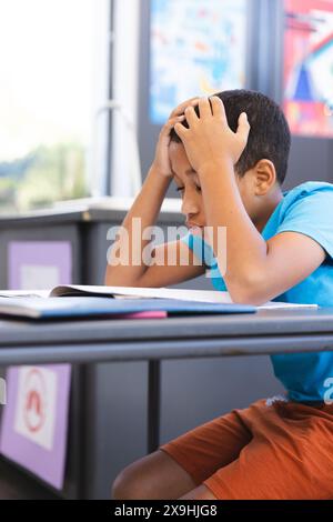 Birassischer Junge sieht frustriert aus von der Schularbeit im Klassenzimmer in der Schule Stockfoto