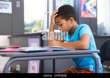 Birassischer Junge, der sich auf die Schularbeit im Klassenzimmer konzentriert Stockfoto