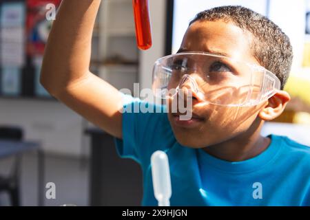 Biracial Boy untersucht ein Reagenzglas in einem Wissenschaftslabor Stockfoto