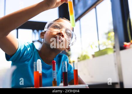 Biracial Boy untersucht ein Reagenzglas in einem Wissenschaftskurs, mit Kopierraum Stockfoto