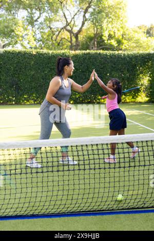 Im Freien gibt es eine rassistische Mutter und Tochter, die High-5 auf dem Tennisplatz geben Stockfoto