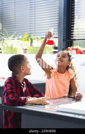 Biracial Girl in orangenem Topfkolben mit roter Flüssigkeit Stockfoto