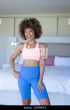 Zu Hause, zweirassige junge Frau in Sportkleidung, stehend im Schlafzimmer Stockfoto